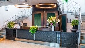 A reception area with a wooden reception desk, a staircase, and a green door. - Hotel Parisi (Nichelino)