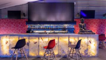 A bar area with a flat-screen TV, a Buddha statue, and three chairs.