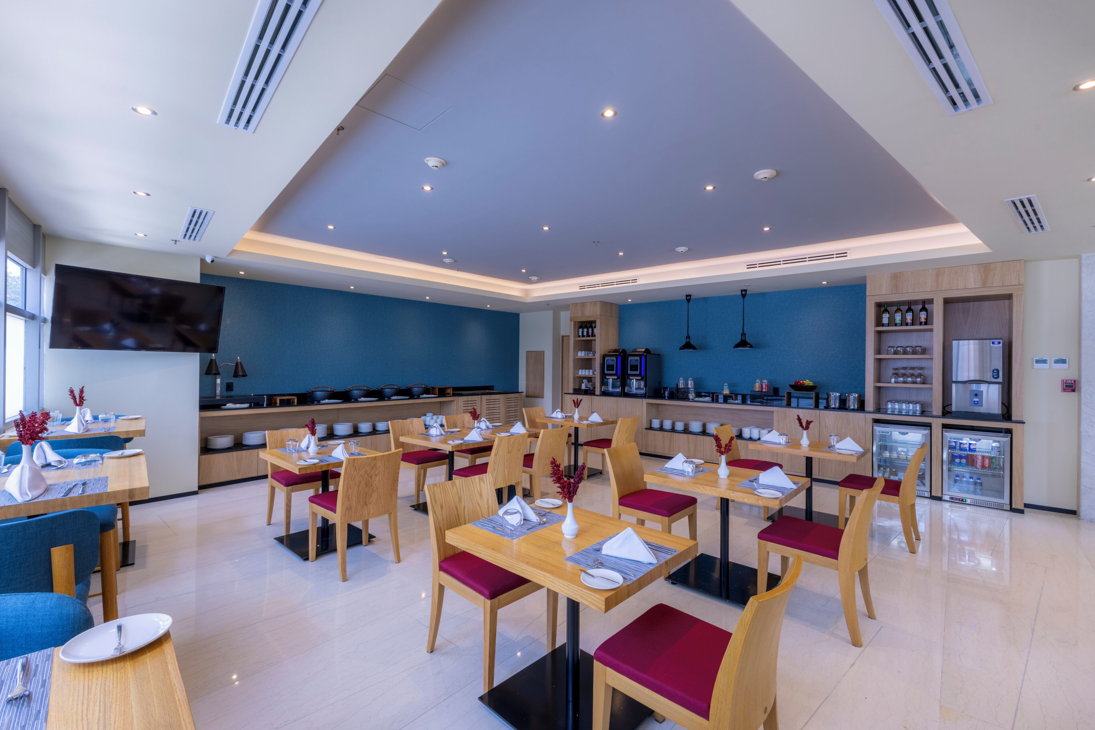 Un restaurante moderno con varias mesas y sillas, una zona de cocina y una barra.