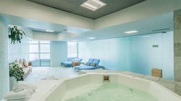 Relax in a serene spa room with a hot tub and lounge chairs offering a view of the outdoors.