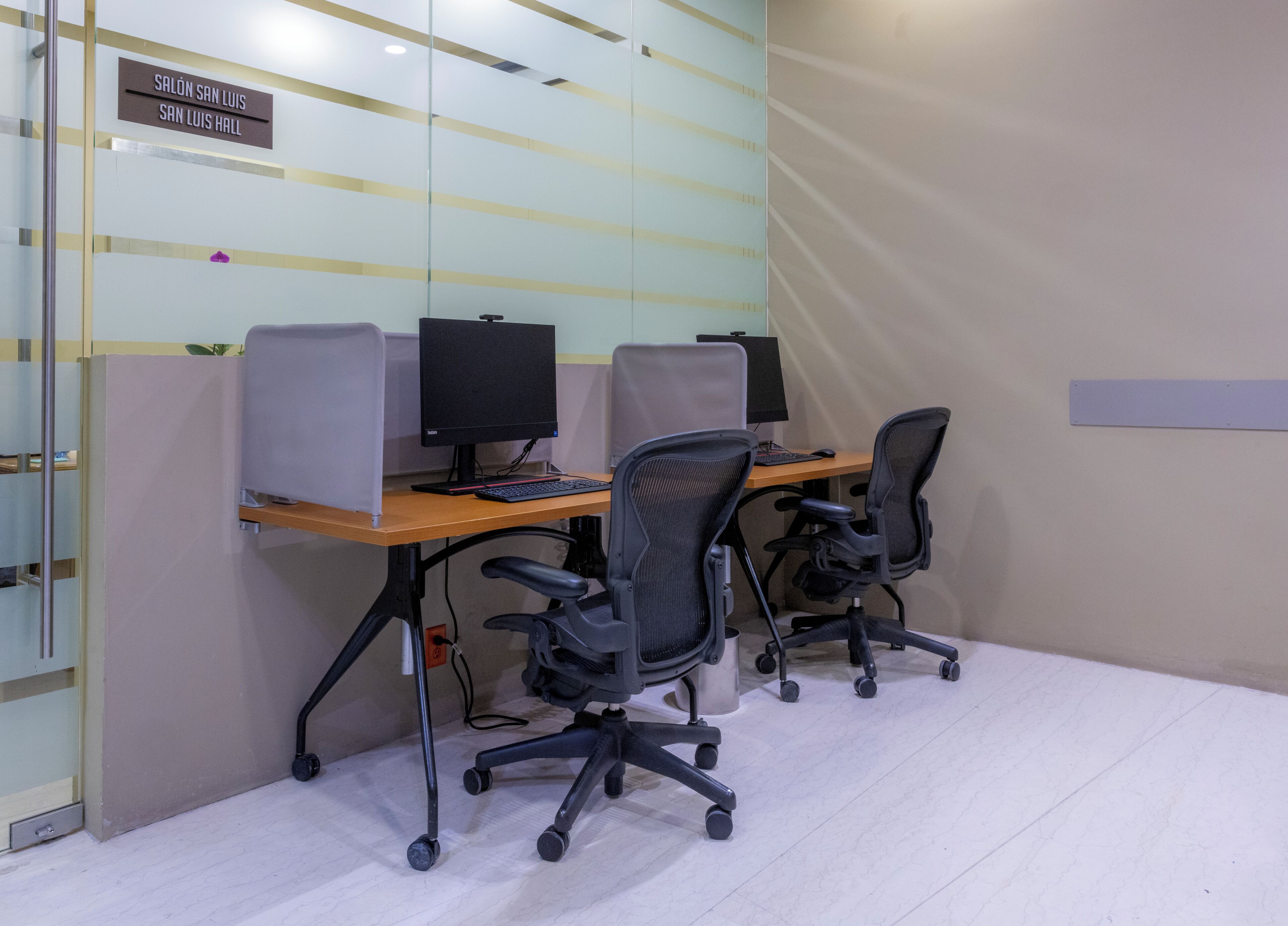 Un espacio de oficina moderno con cubículos, computadoras y sillas ergonómicas.