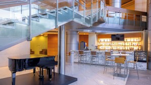 A modern interior with a grand piano, a bar area, and a staircase. - Barceló México Santa Fe (Mexico City)