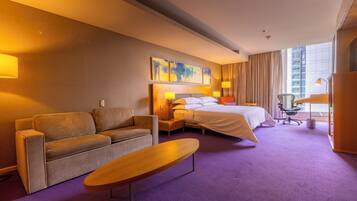 Una habitación de hotel con cama, sofá, una mesita y un escritorio con silla.
