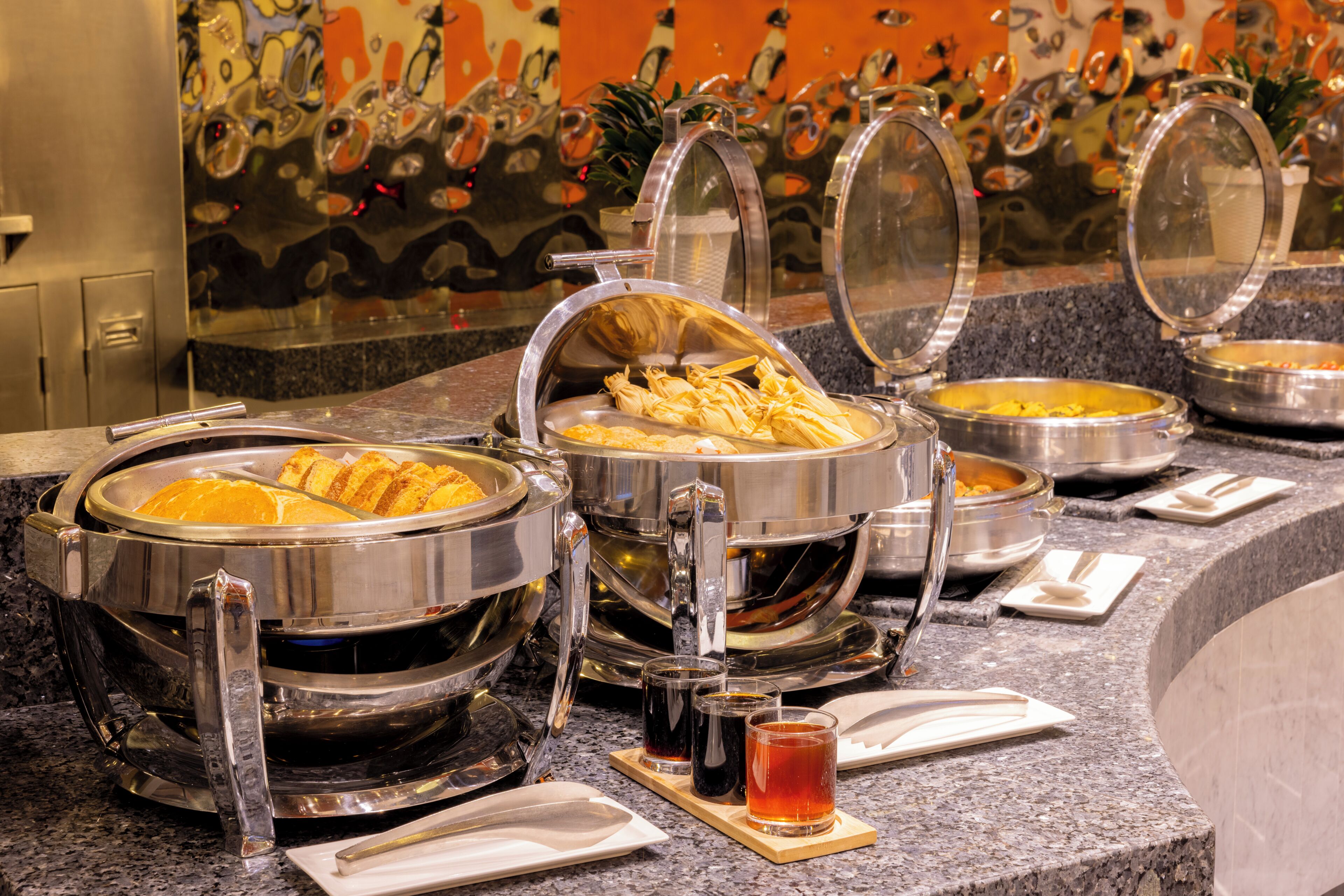 A buffet setup with various food containers and a beverage dispenser.