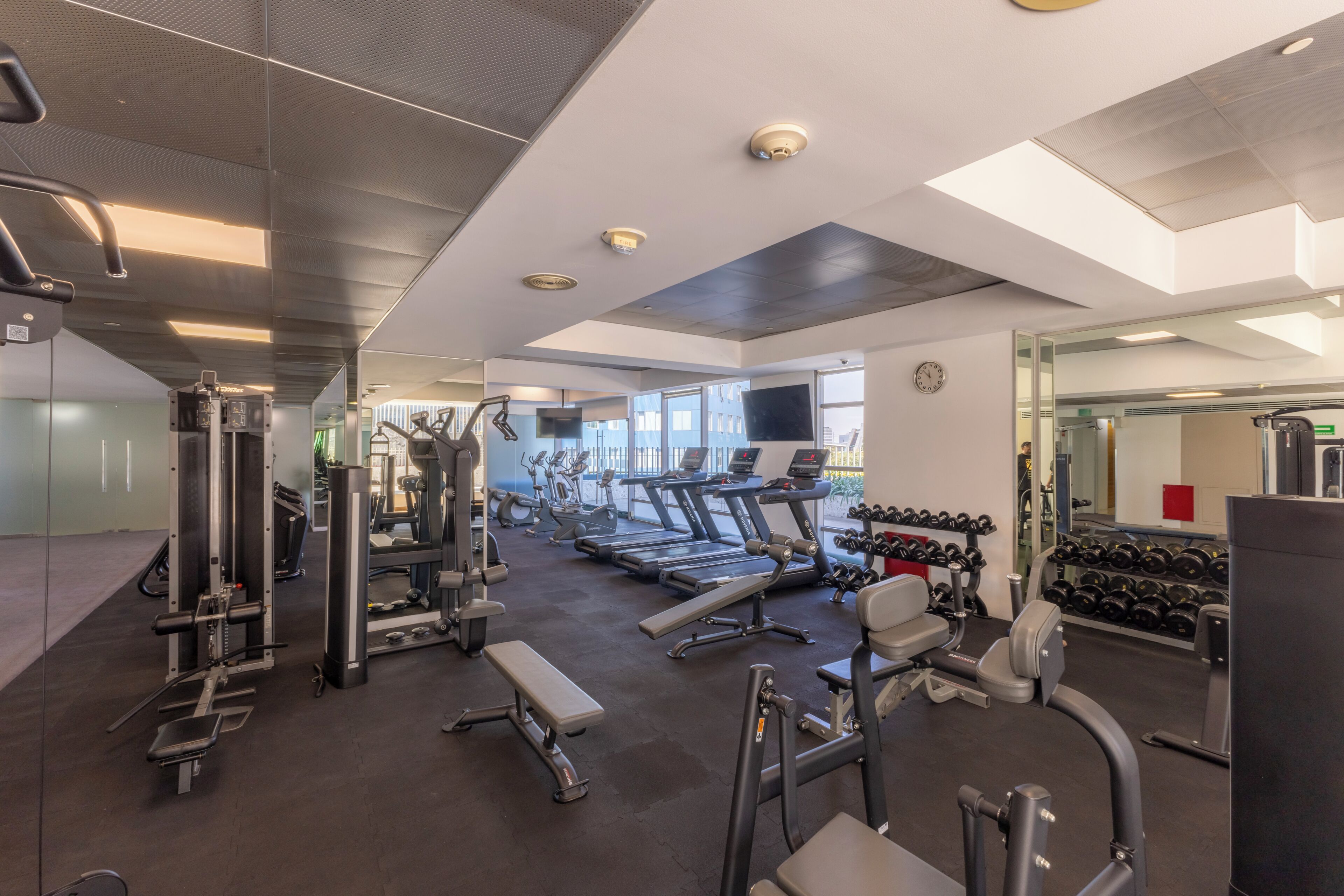 Un gimnasio moderno con diverso equipo de ejercicio, cintas de correr y máquinas de pesas.