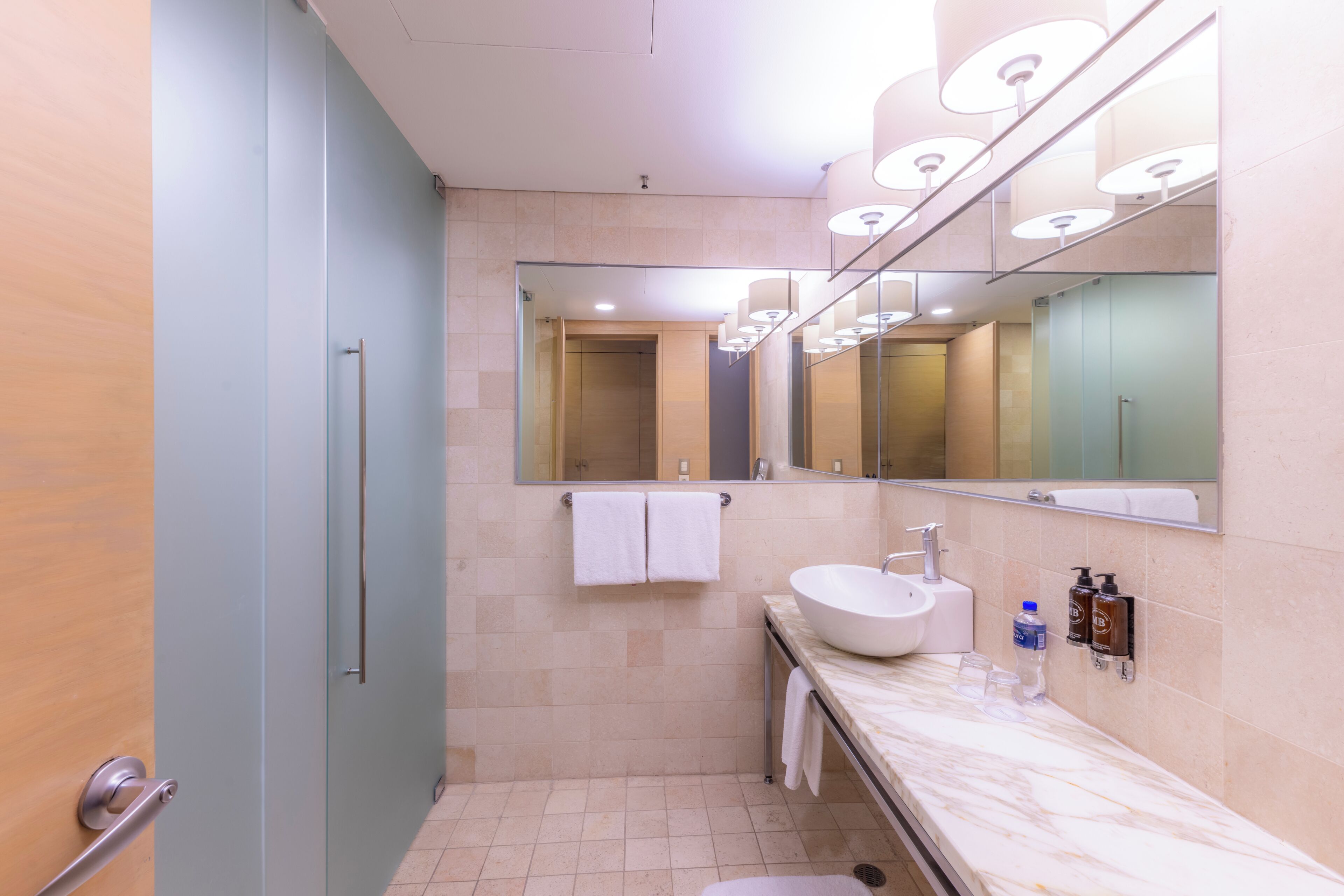 A modern bathroom with a large mirror, a sink, and a shower.