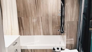 Un baño moderno con bañera, ducha y un taburete de madera con toallas.