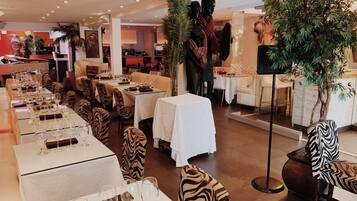 A restaurant with zebra-striped chairs, white tables, and a large tree in the center.