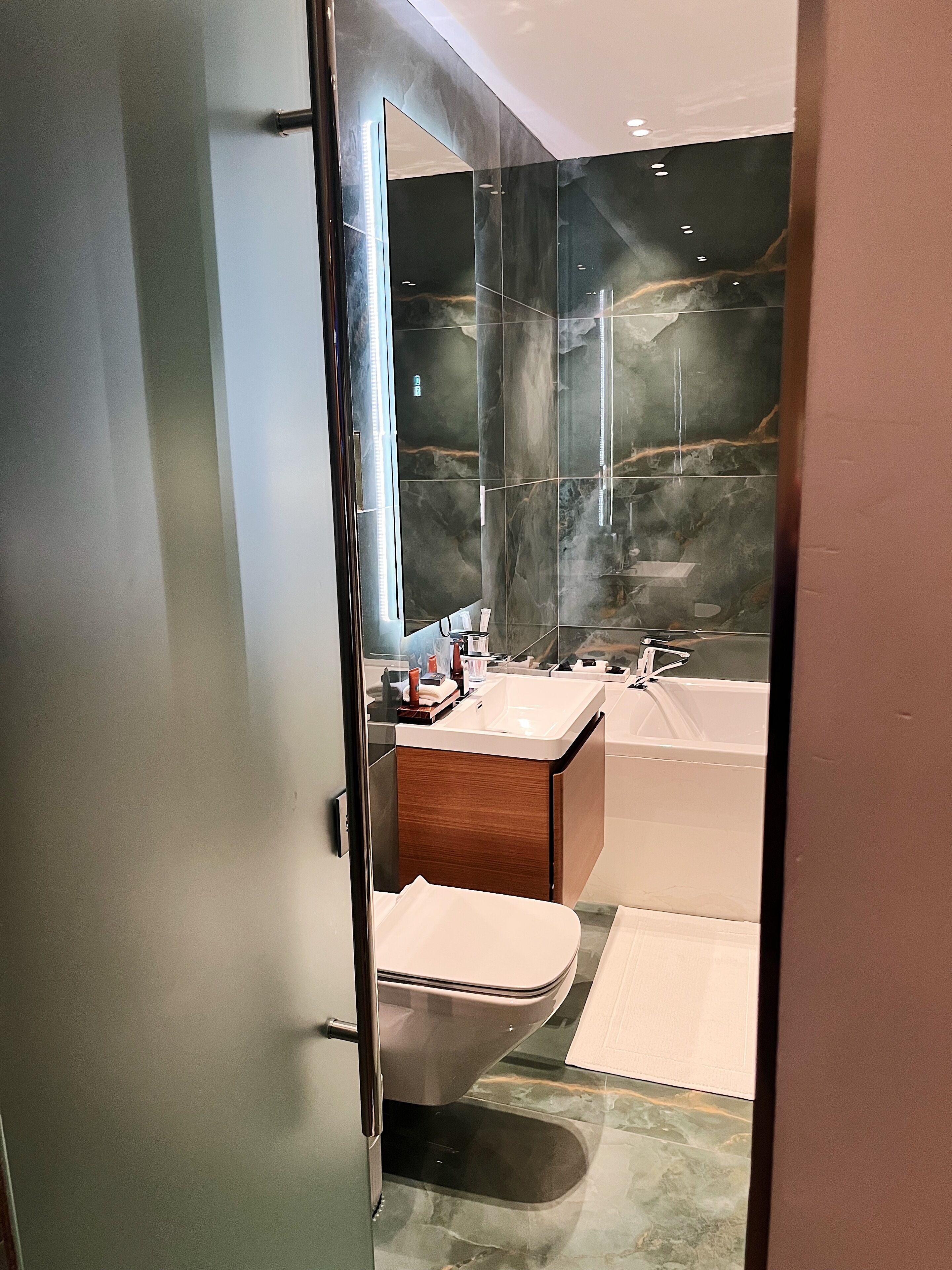 Een moderne badkamer met een douchecabine van glas, een witte wastafel en een bad.
