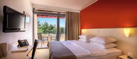 Una habitación de hotel con cama, mesita de noche, televisor y escritorio con teléfono.