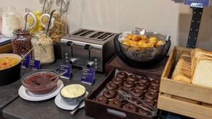 Un bufé con diversas opciones de comida, como cereales, panadería y pasteles.