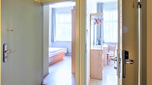 Huoneessa on sänky, tuoli ja työpöytä, jossa on tietokone.