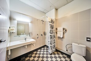 A bathroom with a checkered floor, a glass shower enclosure, a white sink, and a toilet. - Rija Domus Hotel (Riga)