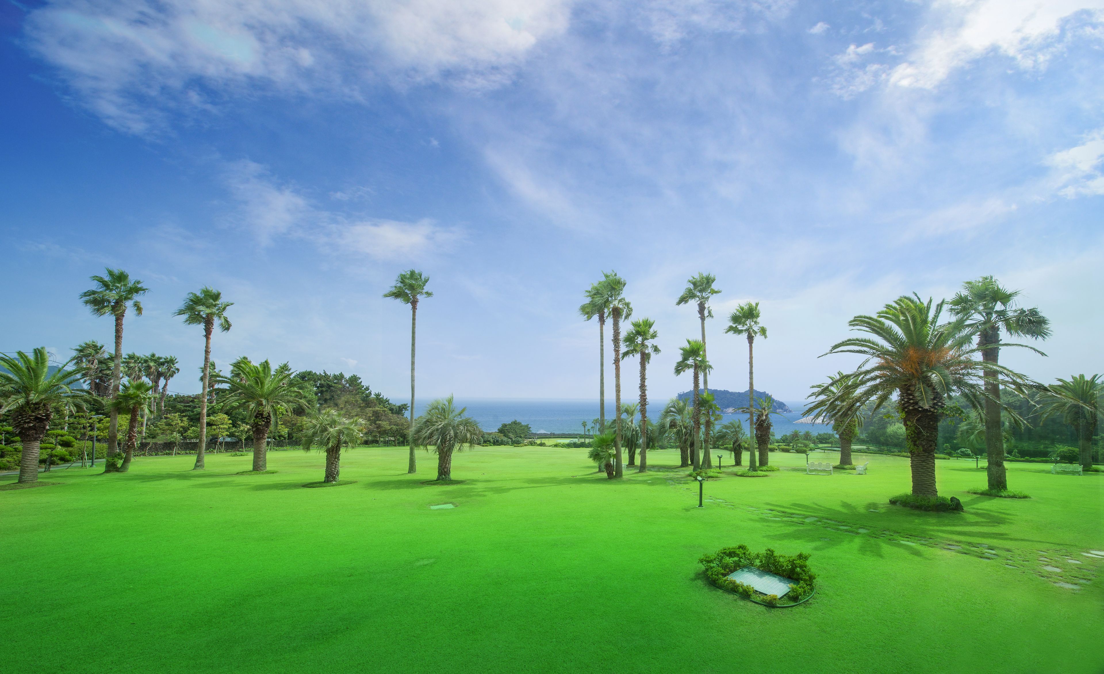 A golf course with a clear view of the ocean and a distant mountain range.