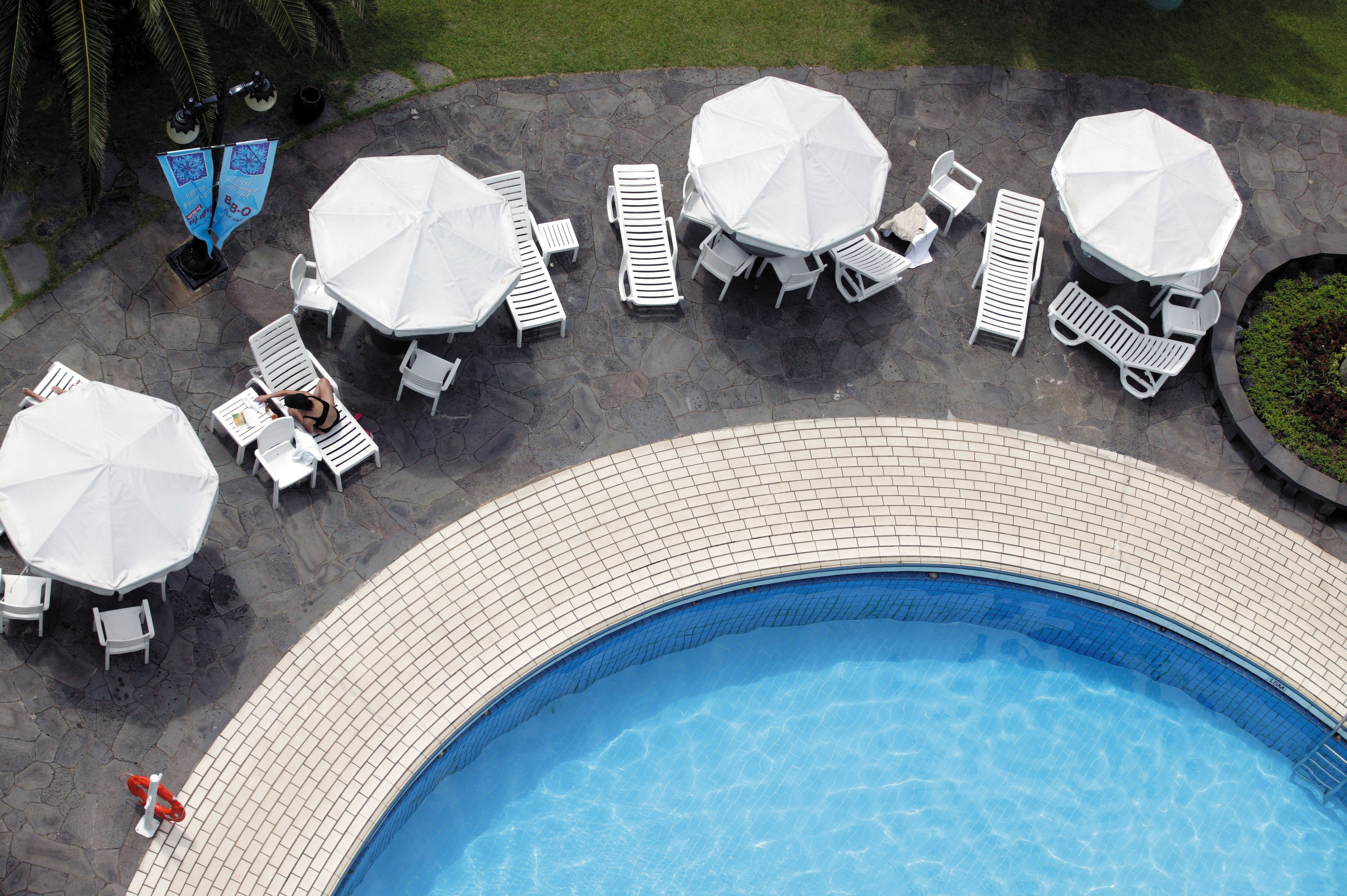A pool area with white lounge chairs, umbrellas, and a tiled deck.