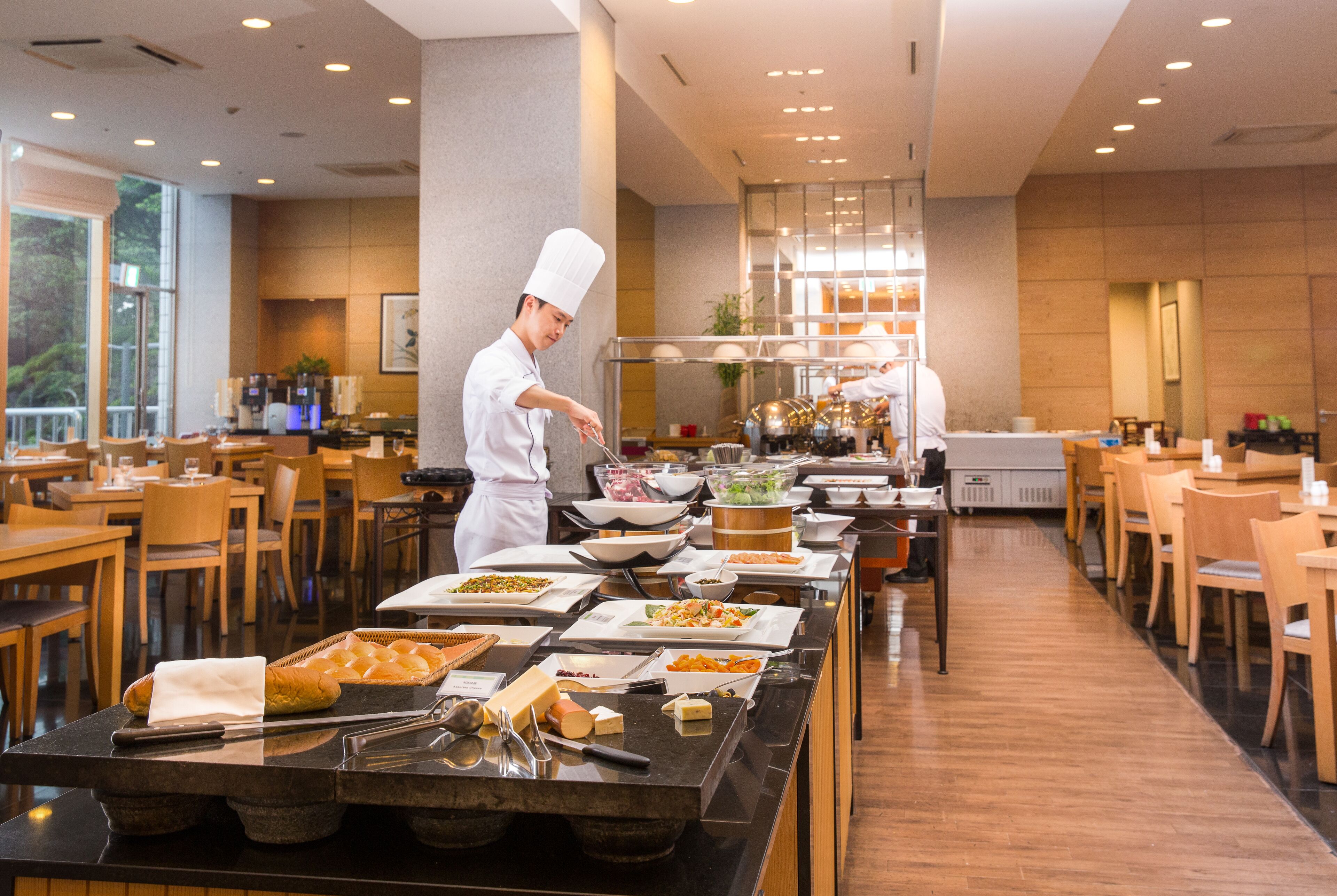 A buffet setup with various food items and a chef preparing food.