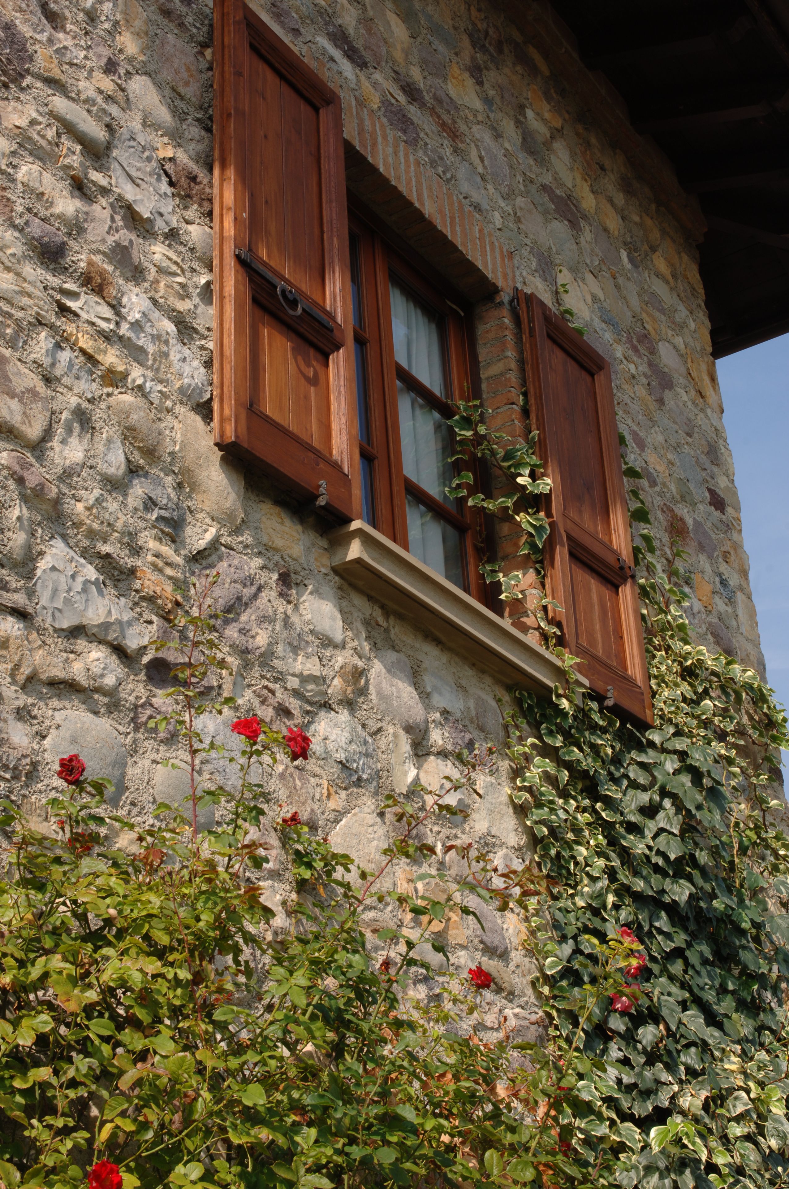 A stone building with wooden shutters and a window.