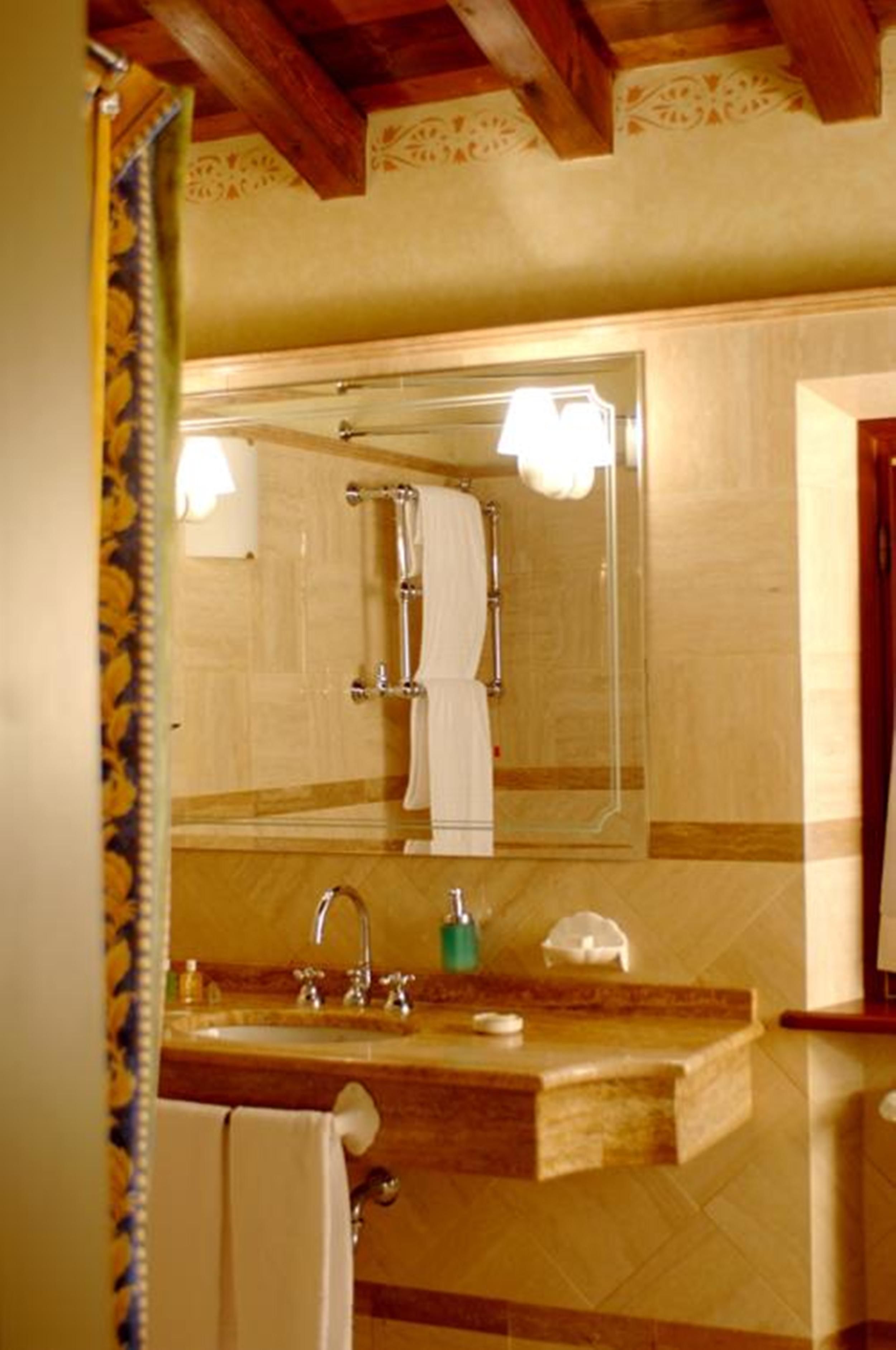 A bathroom with a wooden vanity, a large mirror, and a towel rack.