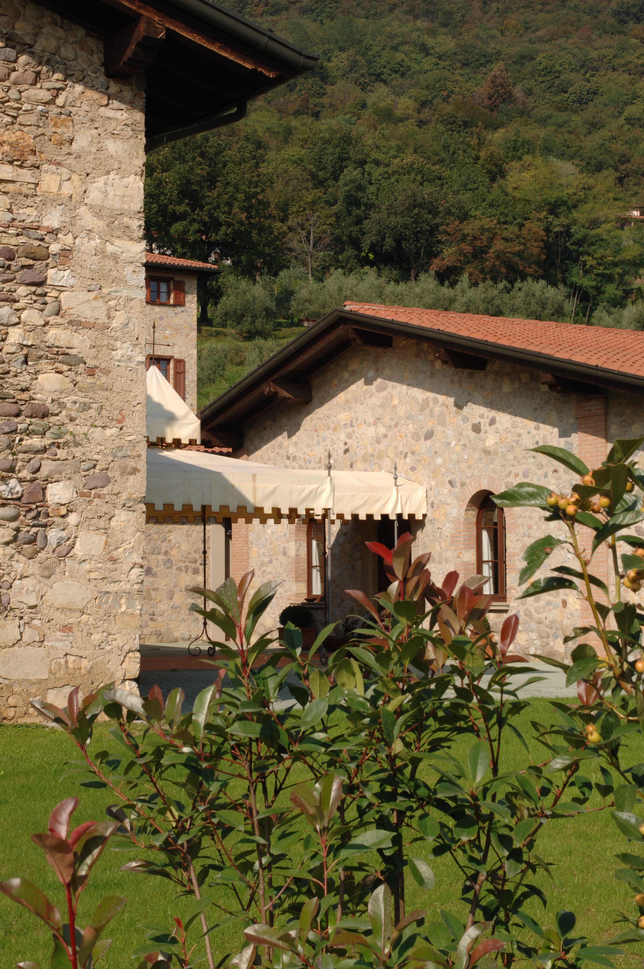 A stone building with a red-tiled roof, a small window, and a white awning.