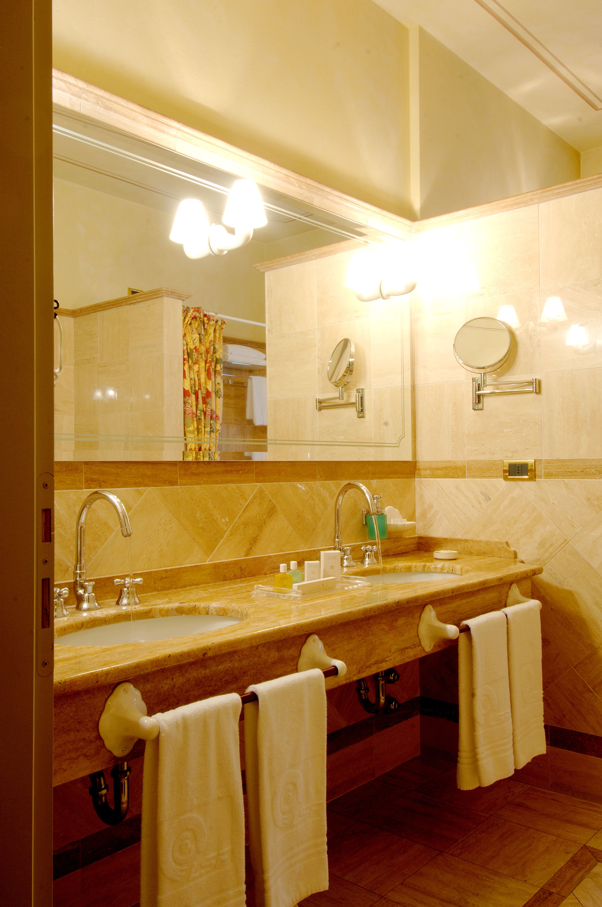 Une salle de bain d’hôtel avec un grand miroir, deux lavabos et plusieurs serviettes.