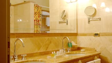 Une salle de bain d’hôtel avec un grand miroir, deux lavabos et plusieurs serviettes.