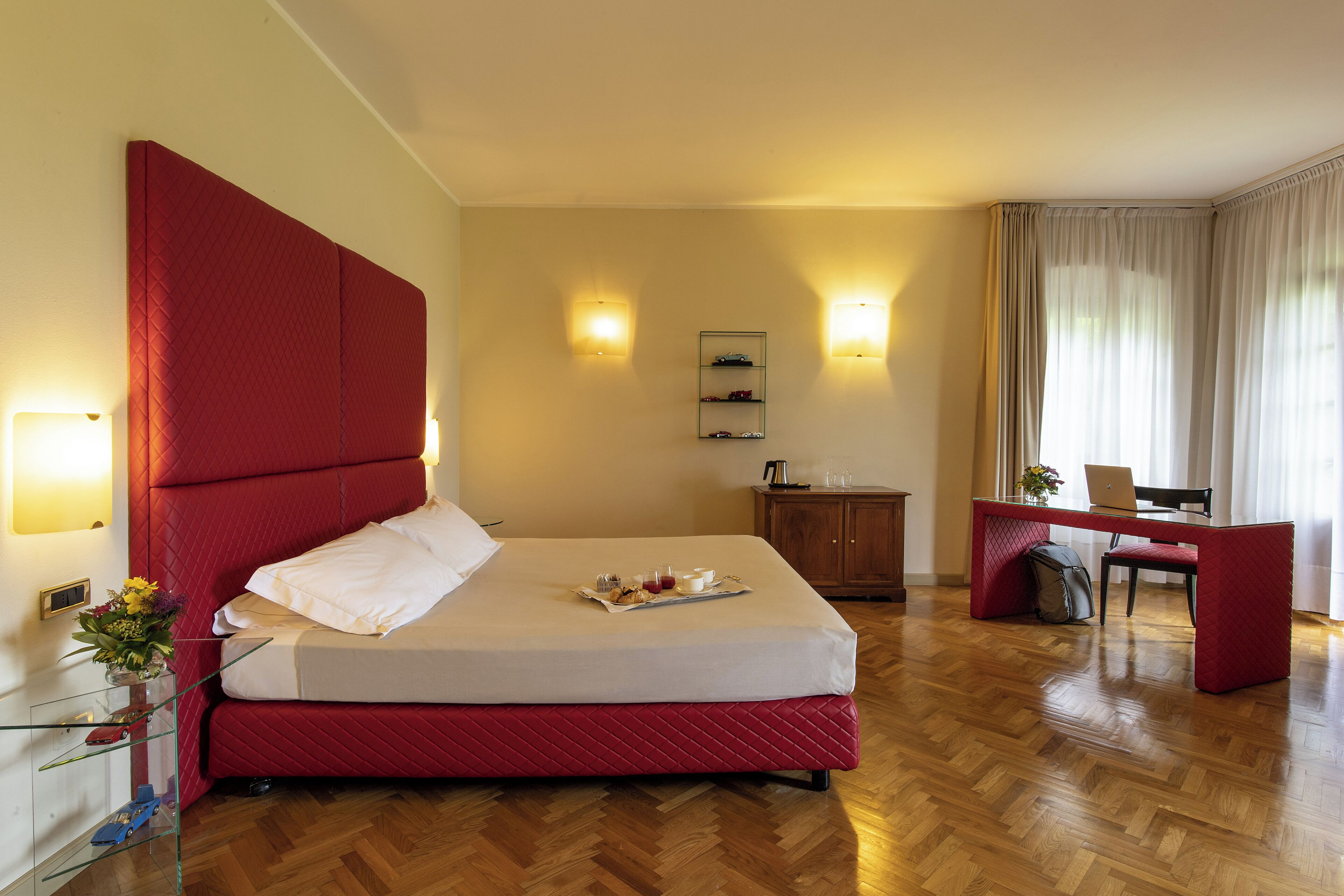 Ein Hotelzimmer mit einem großen Bett, einem Schreibtisch, einem Sessel, einer kleinen Kommode und zwei Wandlampen.