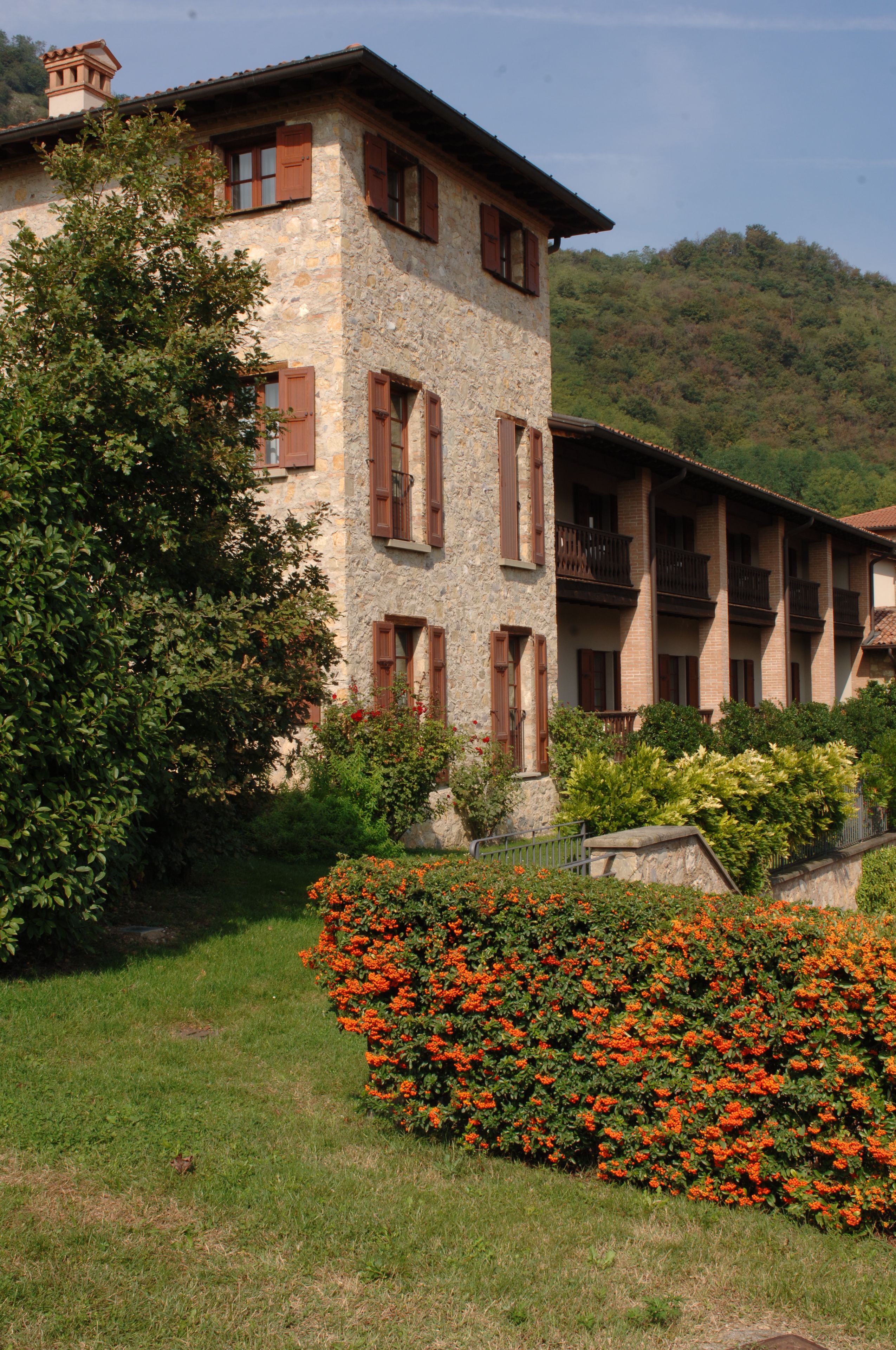 A stone building with multiple balconies and a garden with orange flowers.
