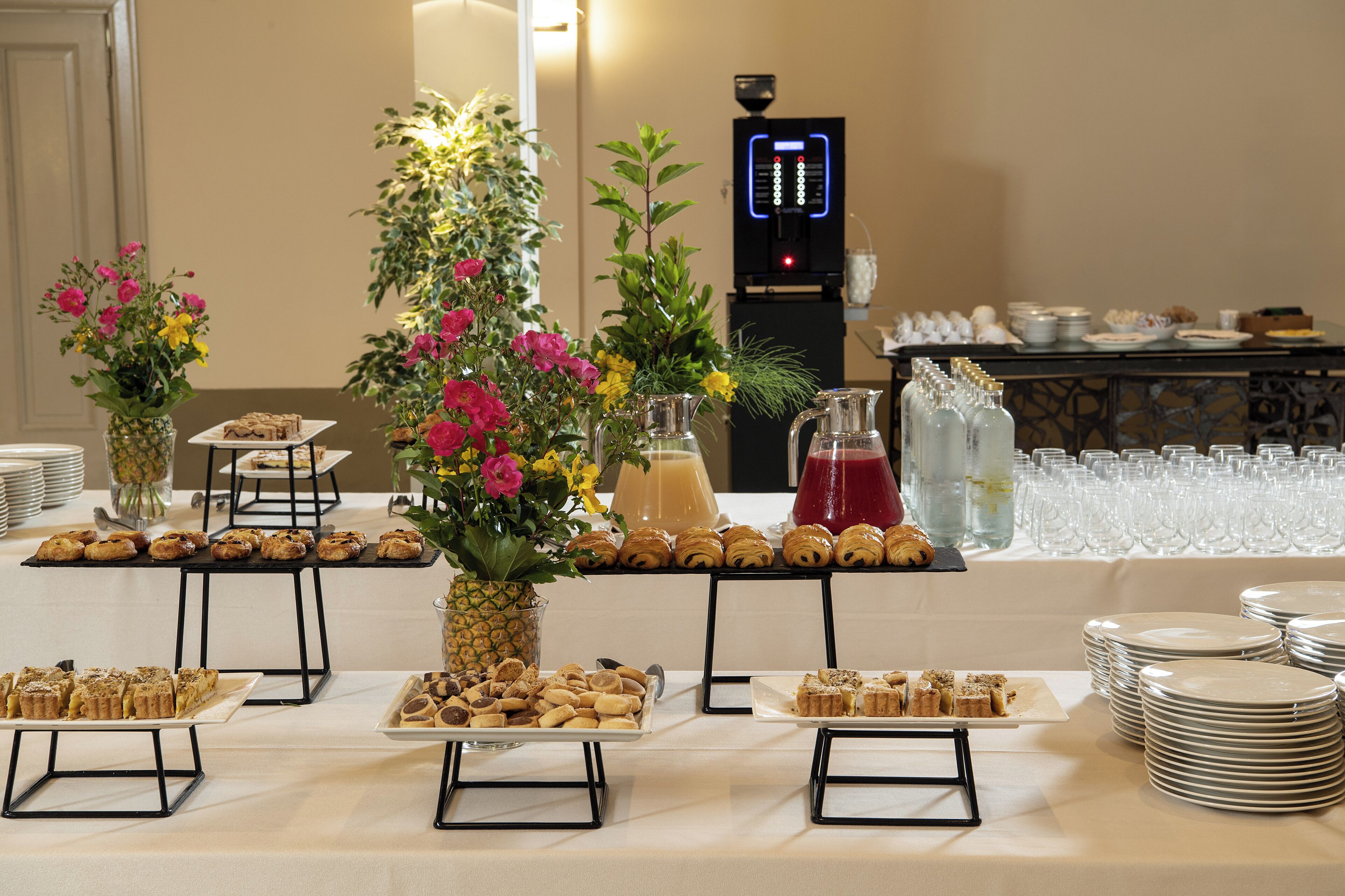 Een buffet met diverse gebakjes, een waterdispenser en een koffieapparaat.