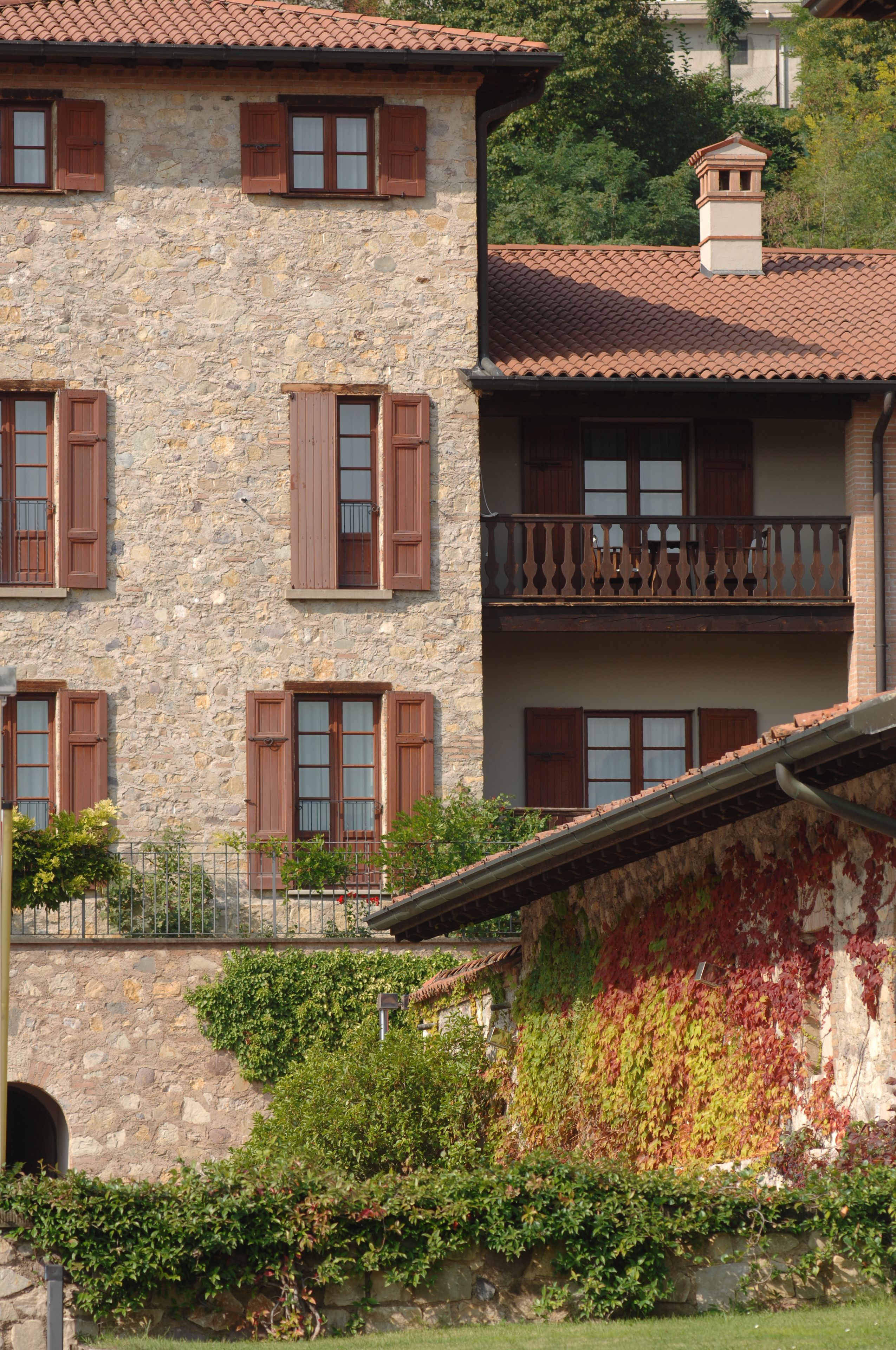 A multi-story stone building with wooden shutters and a balcony.