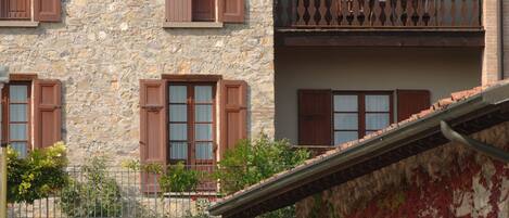 A multi-story stone building with wooden shutters and a balcony.