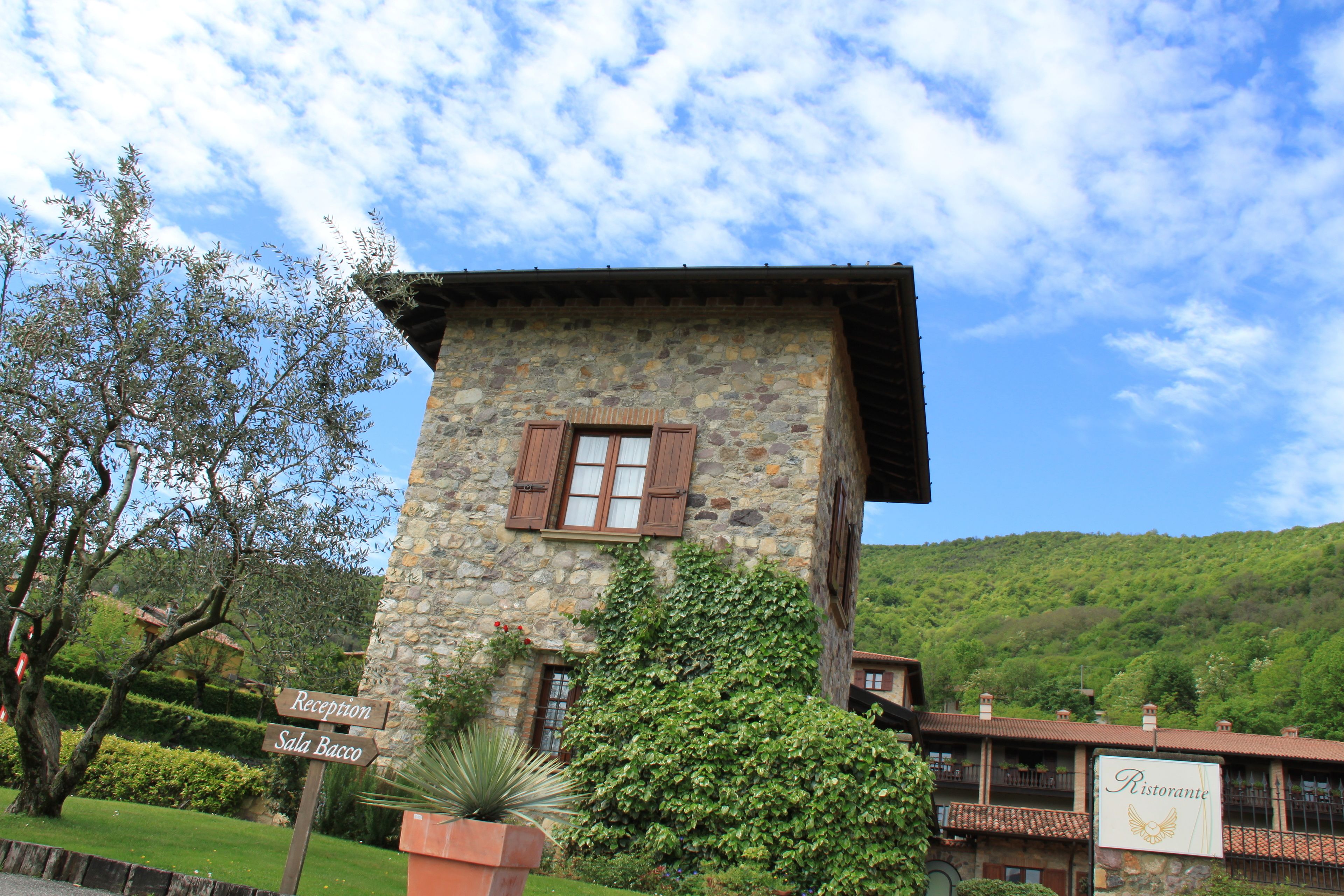 A stone building with a reception sign, surrounded by greenery and a mountainous backdrop.