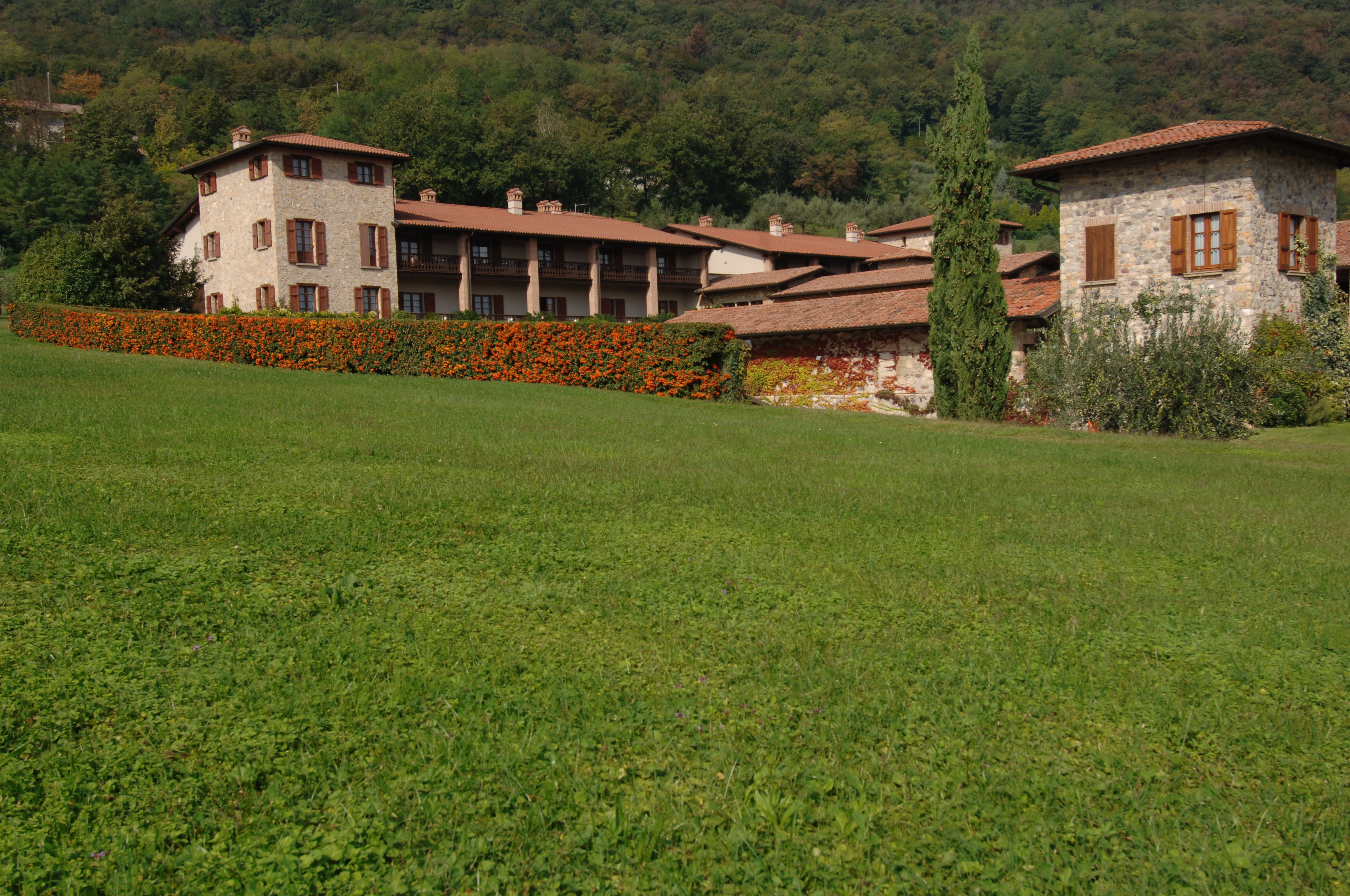 A stone building with multiple balconies and a garden with orange flowers.