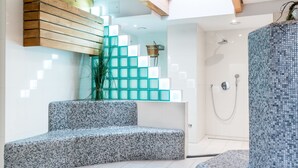 Un baño moderno con cabina de ducha de vidrio, un banco empotrado y una escalera de madera con bloques de vidrio.