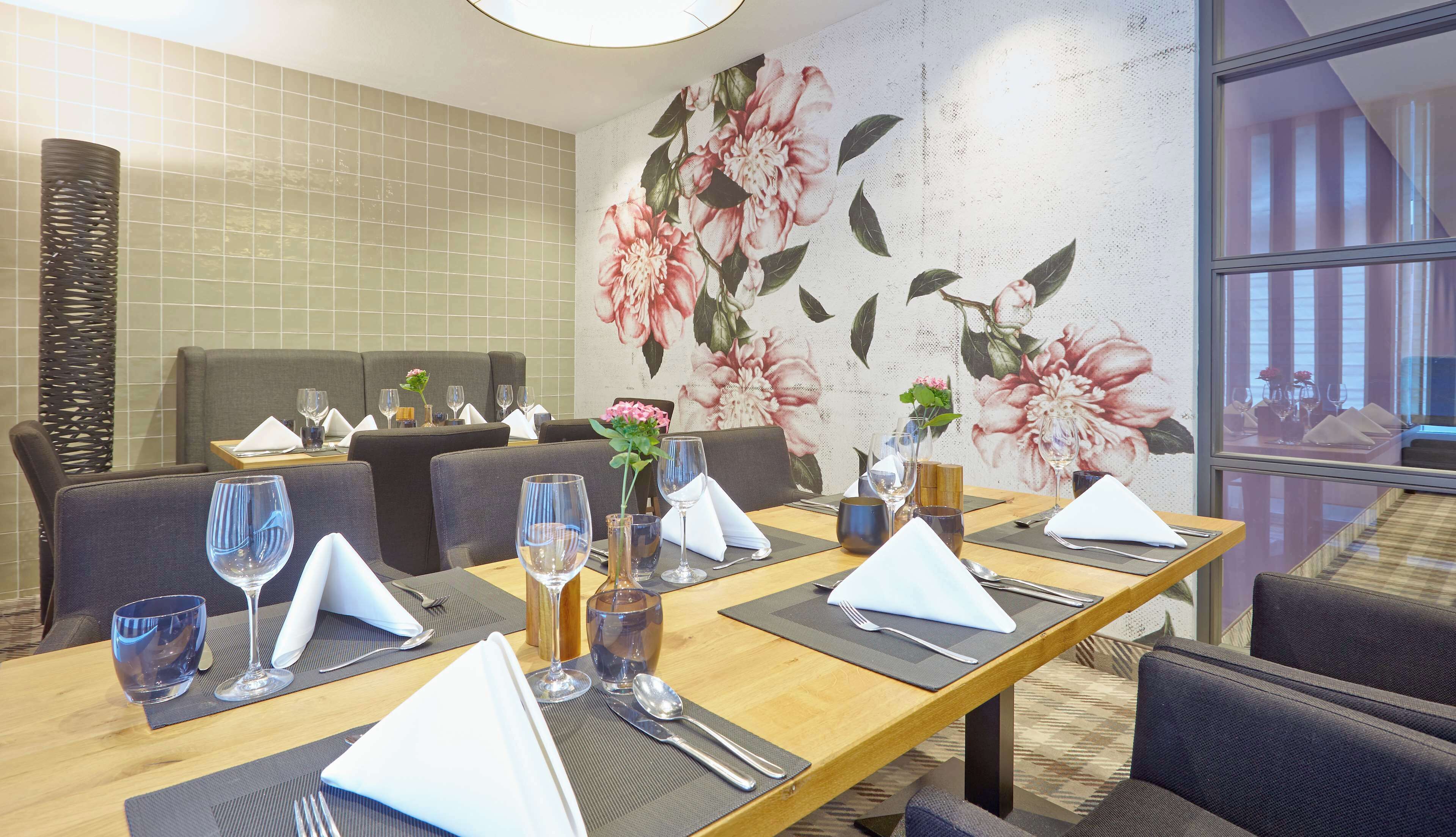 A restaurant with a long table set for a meal, including plates, glasses, and cutlery.