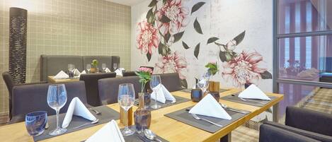 A restaurant with a long table set for a meal, including plates, glasses, and cutlery.