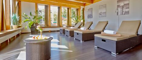 A spa area with wicker lounge chairs, a small fire feature, and large windows with curtains.