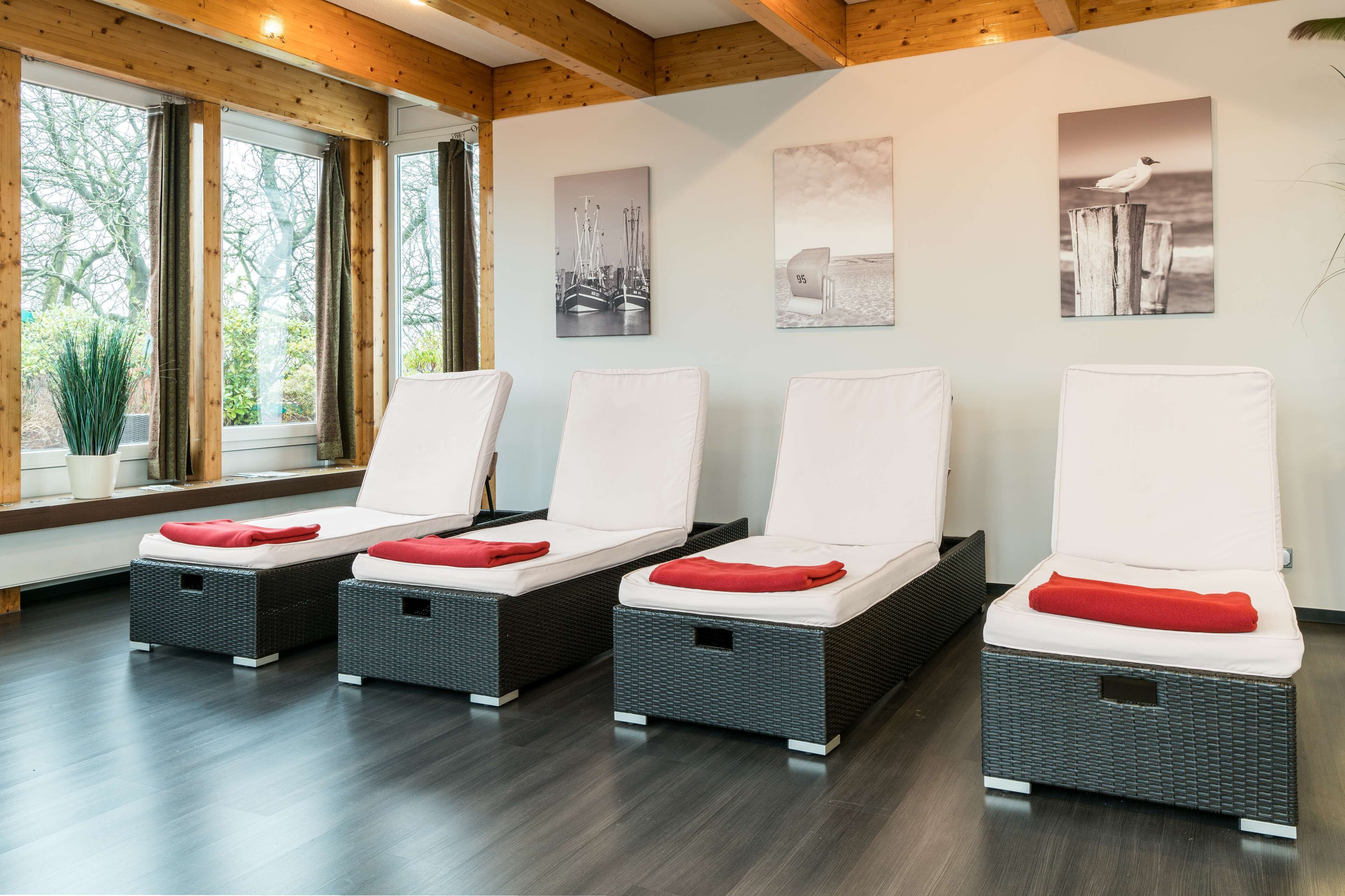 Ein Spa-Raum mit vier Korbsesseln, jeweils mit weißem Kissen und rotem Kopfkissen.