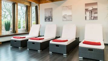 Ein Spa-Raum mit vier Korbsesseln, jeweils mit weißem Kissen und rotem Kopfkissen.