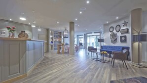 Una cocina moderna con encimera de madera, una zona de comedor con sofá azul y un salón con mesa de centro.
