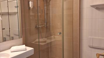 A modern bathroom with a glass-enclosed shower, a white sink, and a toilet.