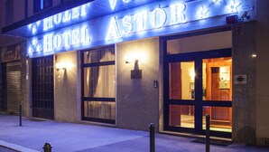 A hotel entrance with a marquee sign reading "HOTEL ASTOR" and a starry design.