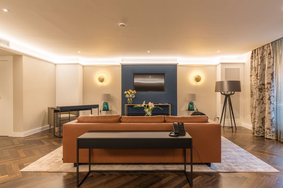 A modern living room with a sofa, coffee table, and a flat-screen TV mounted on the wall.