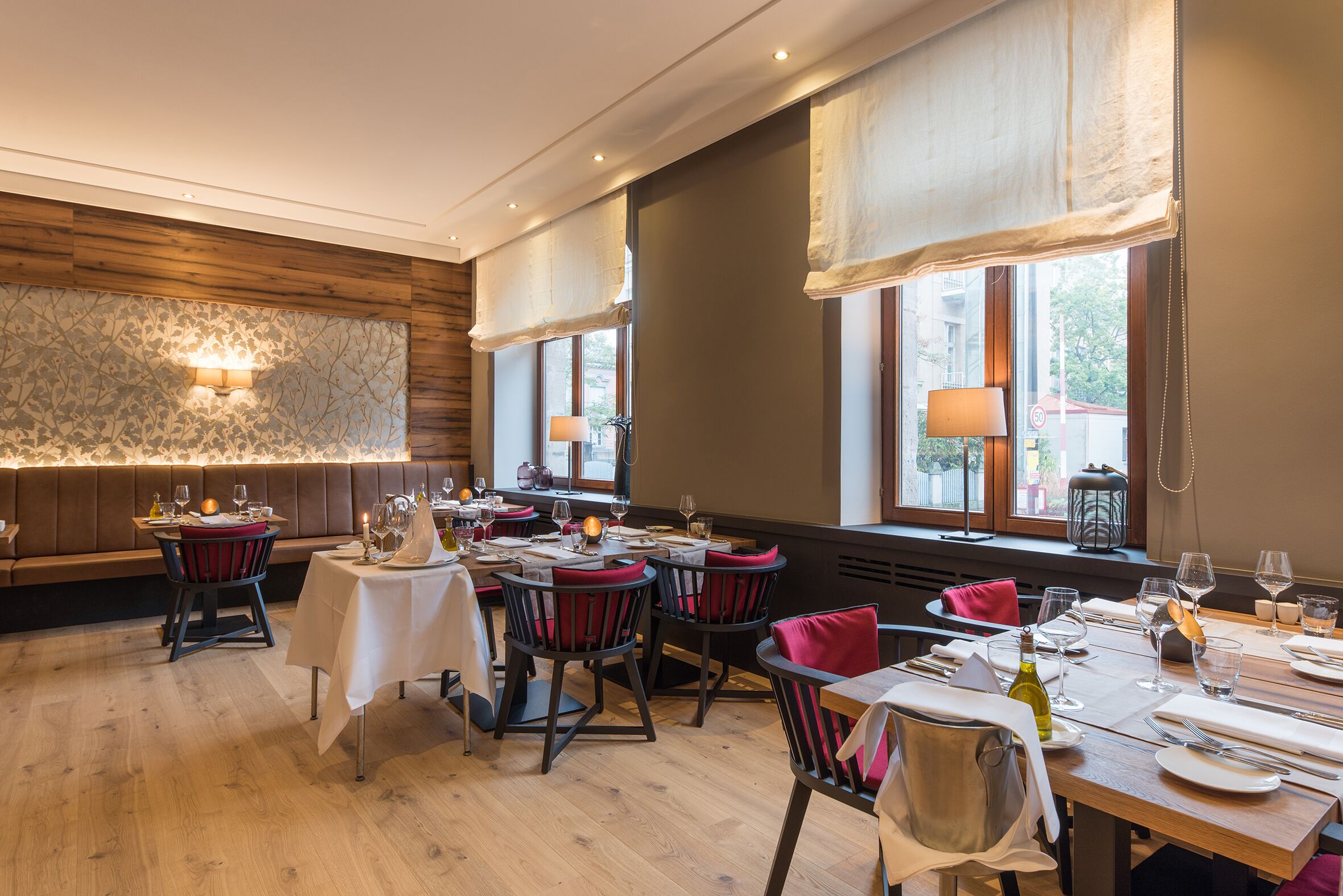 Un restaurant aux murs lambrés, doté de grandes fenêtres avec des rideaux et offrant différents types de sièges, notamment des tables et des chaises.