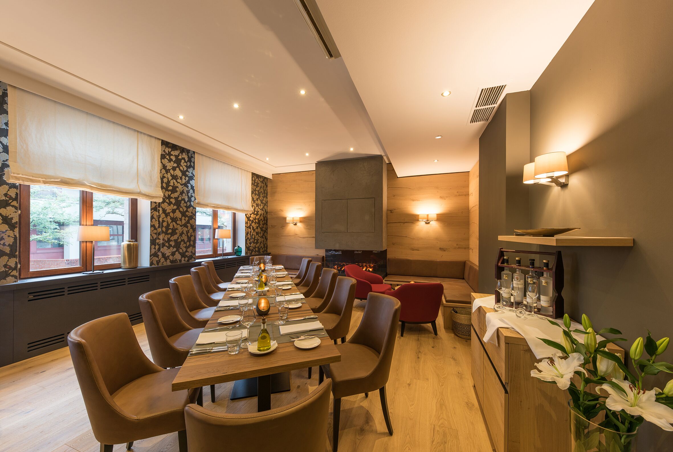 A dining area with a long table, chairs, and a fireplace.