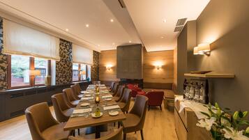 A dining area with a long table, chairs, and a fireplace.