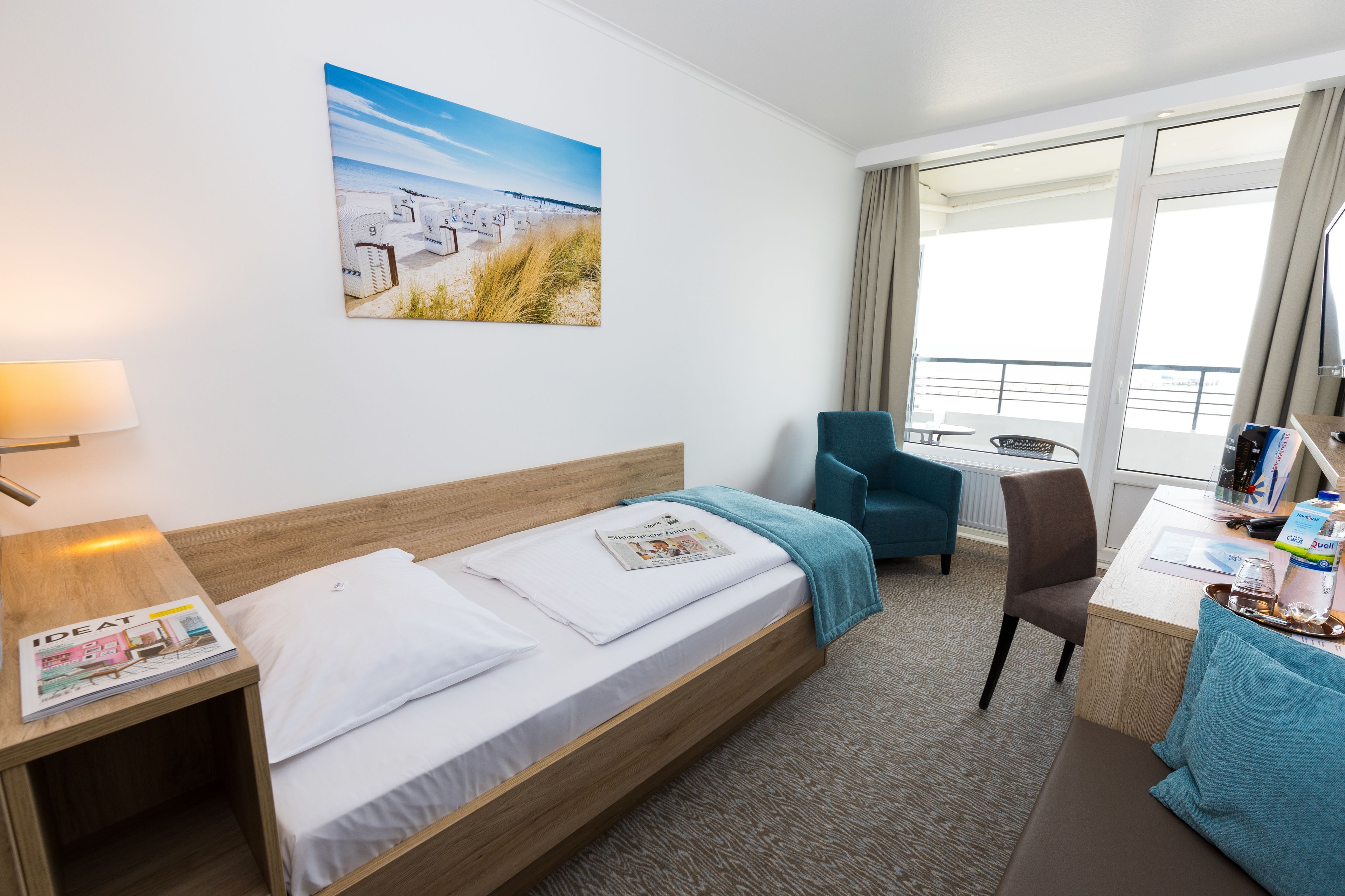 A hotel room with a bed, a desk, a chair, and a large window with curtains.