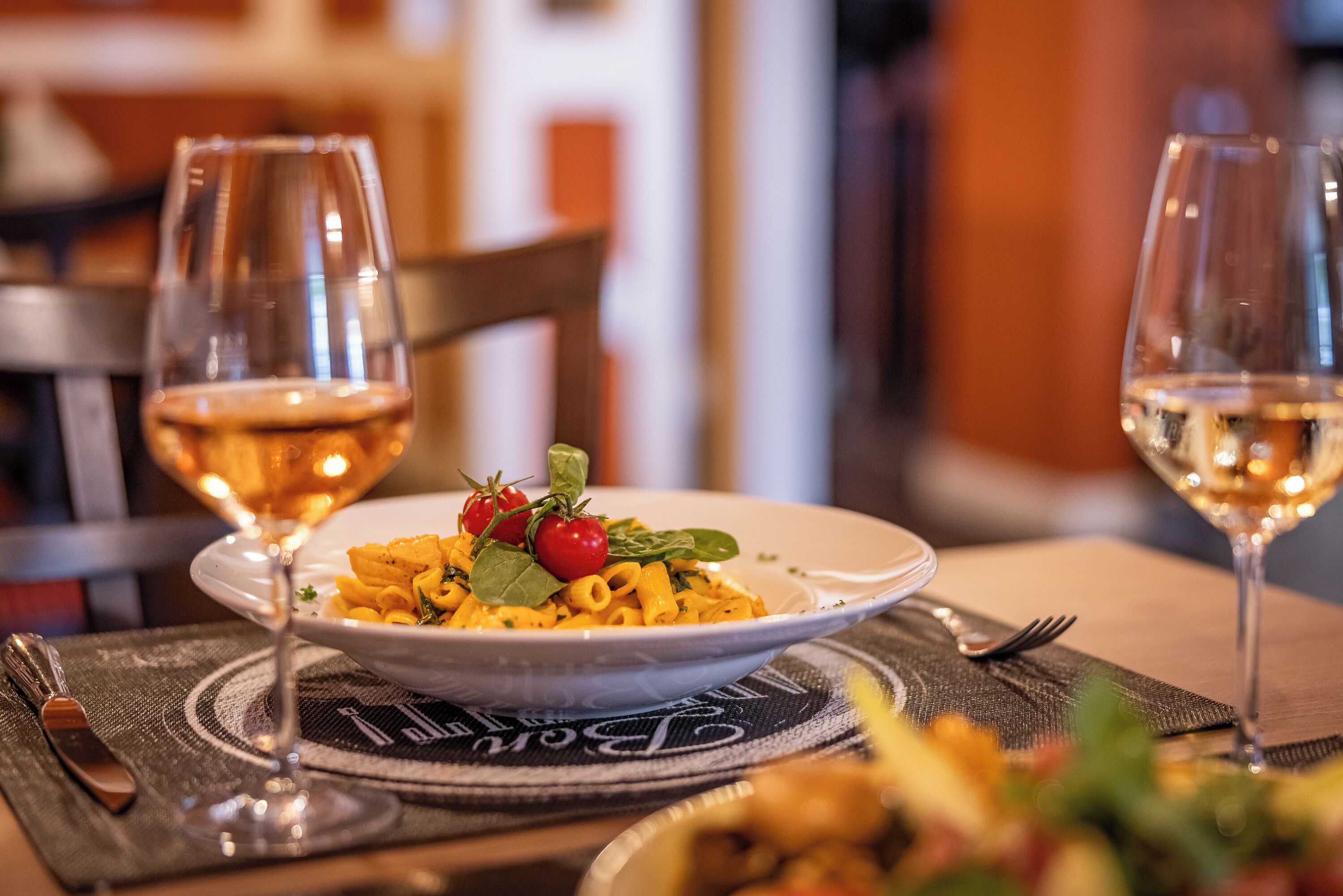Ein Esstisch mit einer Pasta-Zahlung, zwei Weingläsern und einer Gabel.