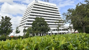 Un hotel de varios pisos con fachada plana, rodeado de vegetación y árboles.