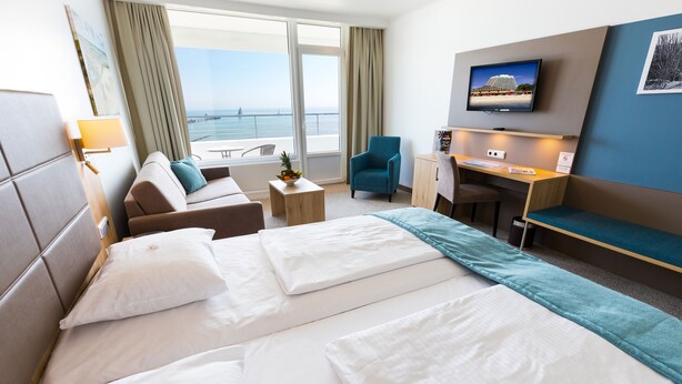 Habitación de hotel con cama, sofá, escritorio, silla y televisor.