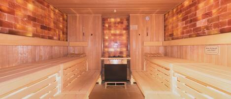 A sauna with wooden benches and a central heating unit.